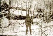 Deutscher Soldat in winterlicher Waldstellung mit Unterständen im Hintergrund
