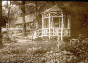 Hölzerner Pavillon mit ornamentalen Verzierungen in bewaldeter Umgebung