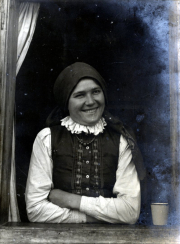 Lächelnde Frau in traditioneller Tracht am Fenster