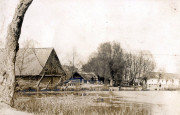 Dorfansicht mit Wasserlauf und traditionellen Holzhäusern im besetzten Gebiet