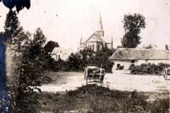 Historisches Dorfleben mit Kirche im Hintergrund und einem Landarbeiter bei der Arbeit