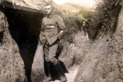 Ein Soldat schreitet durch einen Schützengraben während des Ersten Weltkriegs in einer ruhigen Momentaufnahme