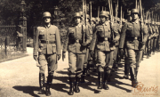 Soldaten in Uniform marschieren stolz durch einen Park im Sommer mit historischen Waffen
