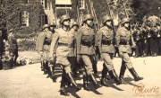 Soldatenparade in historischer Kulisse unter strahlendem Himmel und aufmerksamer Zuschauermenge im Garten eines alten Schlosses