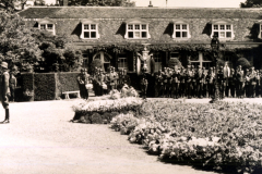 Historische Versammlung im Pfarrgarten mit uniformierten Soldaten und einer Gruppe von Zuschauern