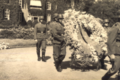 Soldaten bei einer feierlichen Zeremonie mit einer prachtvollen Blumenkranztrage inmitten historischer Architektur