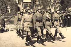 Soldatenparade in historischer Kulisse unter strahlendem Himmel und aufmerksamer Zuschauermenge im Garten eines alten Schlosses