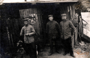 Soldaten in historischer Uniform vor einer einfachen Unterkunft während des Ersten Weltkriegs im ländlichen Europa