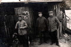 Soldaten in historischer Uniform vor einer einfachen Unterkunft während des Ersten Weltkriegs im ländlichen Europa