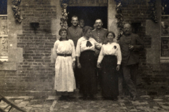 Impressionen aus dem Ersten Weltkrieg mit Zivilisten und Soldaten vor einem Haus in der Nähe der Front