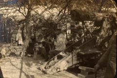 Soldaten des Ersten Weltkriegs arbeiten in einem Feldlager, umgeben von Bäumen und militärischen Ausrüstungen