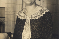 Ein Porträt einer lächelnden Frau in einem eleganten Kleid mit Spitzenkragen aus den 1920er Jahren