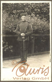 Soldat im Ersten Weltkrieg in uniformierter Pose vor einer Hecke