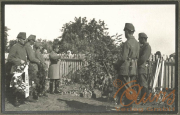 Soldaten gedenken Gefallener im Ersten Weltkrieg an einem Grab mit Kränzen in einer ländlichen Umgebung