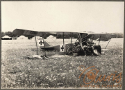 Verunglücktes Flugzeug des Ersten Weltkriegs auf einem Feld, umgeben von Zeltlagern und Graslandschaft