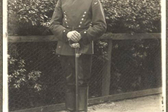 Soldat im Ersten Weltkrieg in uniformierter Pose vor einer Hecke