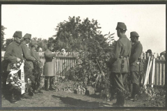 Soldaten gedenken Gefallener im Ersten Weltkrieg an einem Grab mit Kränzen in einer ländlichen Umgebung