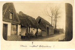 Soldaten im Ersten Weltkrieg vor einem zerstörten Gebäude in einer ländlichen Umgebung