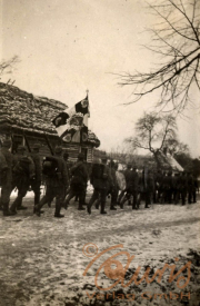 Soldaten des Ersten Weltkriegs marschieren in einer verschneiten Landschaft entlang einer Dorfstraße