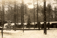 Soldaten stehen im Schnee vor einem Schützengraben des Ersten Weltkriegs in einem Waldgebiet
