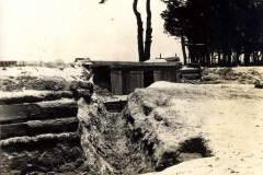 Blick auf einen Schützengraben im Ersten Weltkrieg, umgeben von Bäumen und Schnee im winterlichen Gelände