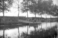 Soldaten während des Ersten Weltkriegs auf einem Boot am Ufer eines Gewässers mit Bäumen