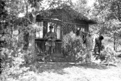 Soldaten des Ersten Weltkriegs stehen vor einer Holzunterkunft in ländlicher Umgebung