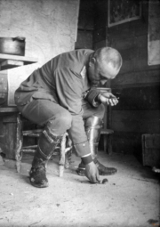 Soldat im Ersten Weltkrieg bei der Arbeit in einem Unterstand, umgeben von militärischer Ausrüstung und persönlichen Gegenständen