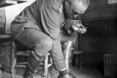 Soldat im Ersten Weltkrieg bei der Arbeit in einem Unterstand, umgeben von militärischer Ausrüstung und persönlichen Gegenständen