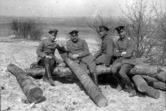 Soldaten sitzen auf Baumstämmen während des Ersten Weltkriegs in einer ländlichen Umgebung