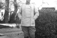 Soldat im Ersten Weltkrieg posiert in Uniform vor einem Garten in Europa