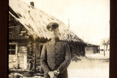 Soldat im Ersten Weltkrieg vor einem traditionellen Holzhaus in