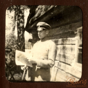 Soldat liest eine Karte vor einer Holzbaracke während des Ersten Weltkriegs