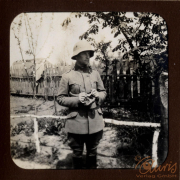 Ein Soldat des Ersten Weltkriegs in Uniform steht in einem Garten mit Holzzaun und beobachtet die Umgebung