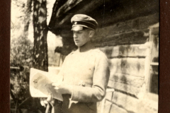 Soldat liest eine Karte vor einer Holzbaracke während des Ersten Weltkriegs