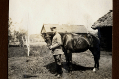 Soldat des Ersten Weltkriegs mit Pferd vor einer Unterkunft in ländlicher Umgebung