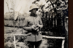 Ein Soldat des Ersten Weltkriegs in Uniform steht in einem Garten mit Holzzaun und beobachtet die Umgebung