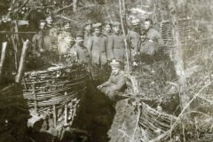 Eine Gruppe von Soldaten im Schützengraben während des Ersten Weltkriegs in einem bewaldeten Gelände