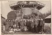 Gruppenfoto von Marineoffizieren und -mannschaften vor industrieller Förderanlage