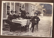 Gruppensitzung von sechs Männern in Uniform bei einem Tisch im Freien in der historischen Umgebung