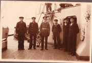 Sechs Männer der Marine stehen auf dem Deck eines Schiffs in historischer Kleidung