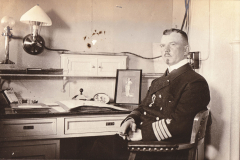 Matrose in Uniform sitzt an einem Schreibtisch in einem maritimen Raum im frühen 20. Jahrhundert