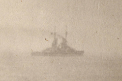 Schiffsnebel über dem Meer mit Silhouette eines Kriegsschiffes während des Morgengrauens