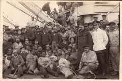 Gruppenaufnahme von Seeleuten während ihrer Dienstzeit auf einem Schiff in historischer Kulisse