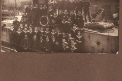 Gruppenfoto der Marinecrew vor einem Schiff im Hafen während des frühen 20. Jahrhunderts