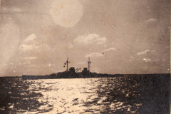 Kriegsschiff auf dem Wasser während des Hafenanlaufes bei Sonnenuntergang