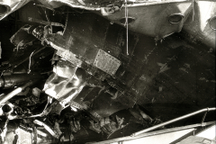 Die Aufnahme zeigt das völlig verwüstete Innere eines Kriegsschiffes mit verbogenen Metallteilen, Trümmern und zerstörten Aufbauten. Die schweren Schäden deuten auf Kampfeinwirkung oder Explosion hin.