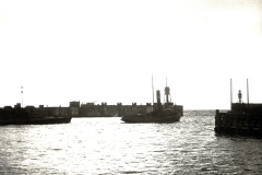 Ein Kriegsschiff mit charakteristischen Masten und Schornstein liegt zwischen zwei Hafenmolen. Die Aufnahme entstand im Kontext der deutschen U-Boot-Operationen im Mittelmeer während des Ersten Weltkriegs.