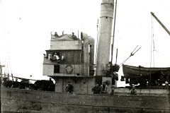 Ein deutsches Torpedoboot der Kaiserlichen Marine mit mehreren Besatzungsmitgliedern auf Deck und Brücke. Das Kriegsschiff zeigt typische Aufbauten mit Schornstein, Brückenhaus und Rettungsboot an Deck.