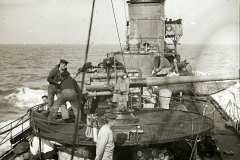 Das Torpedoboot G 92 zeigt seine Besatzung bei der Bedienung des Heckgeschützes während einer Fahrt auf See. Die Aufnahme dokumentiert die Geschützbedienung und den Aufbau des Kriegsschiffes im Ersten Weltkrieg.